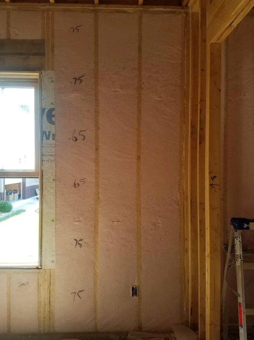 Netted blown-in wall insulation beside a framed window opening