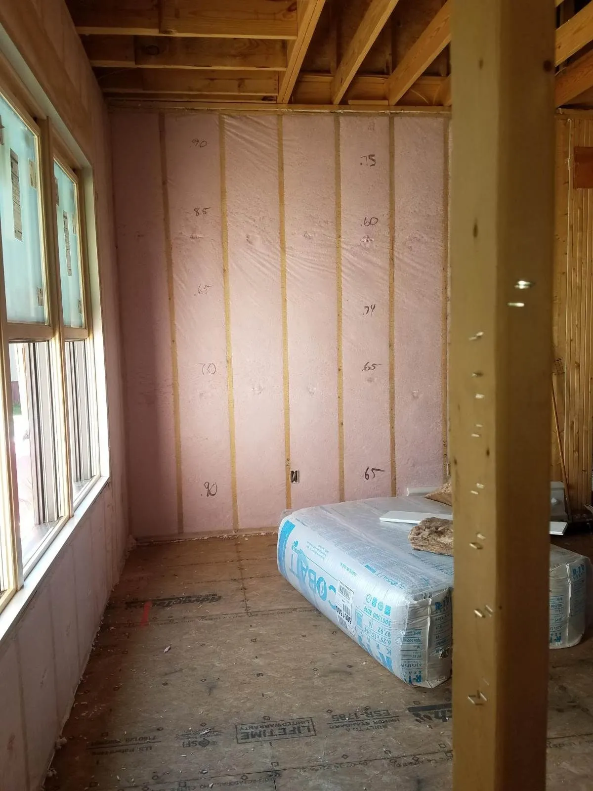 Blown-in blanket insulation in the walls of a framed room with window openings