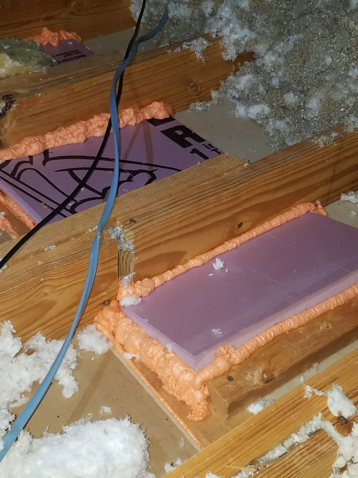 Rigid foam board air-sealed with spray foam around an opening in an attic floor
