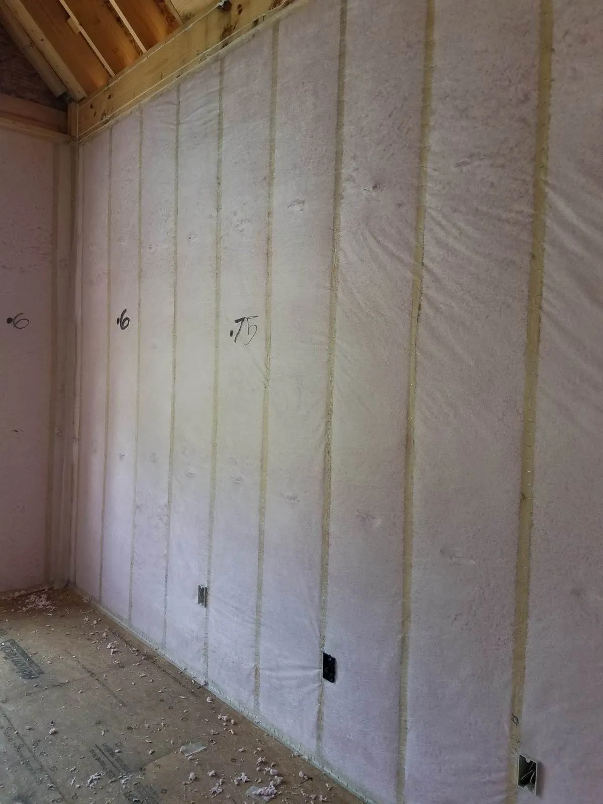Blown-in blanket insulation in the walls of a framed room, depth marked on the netting