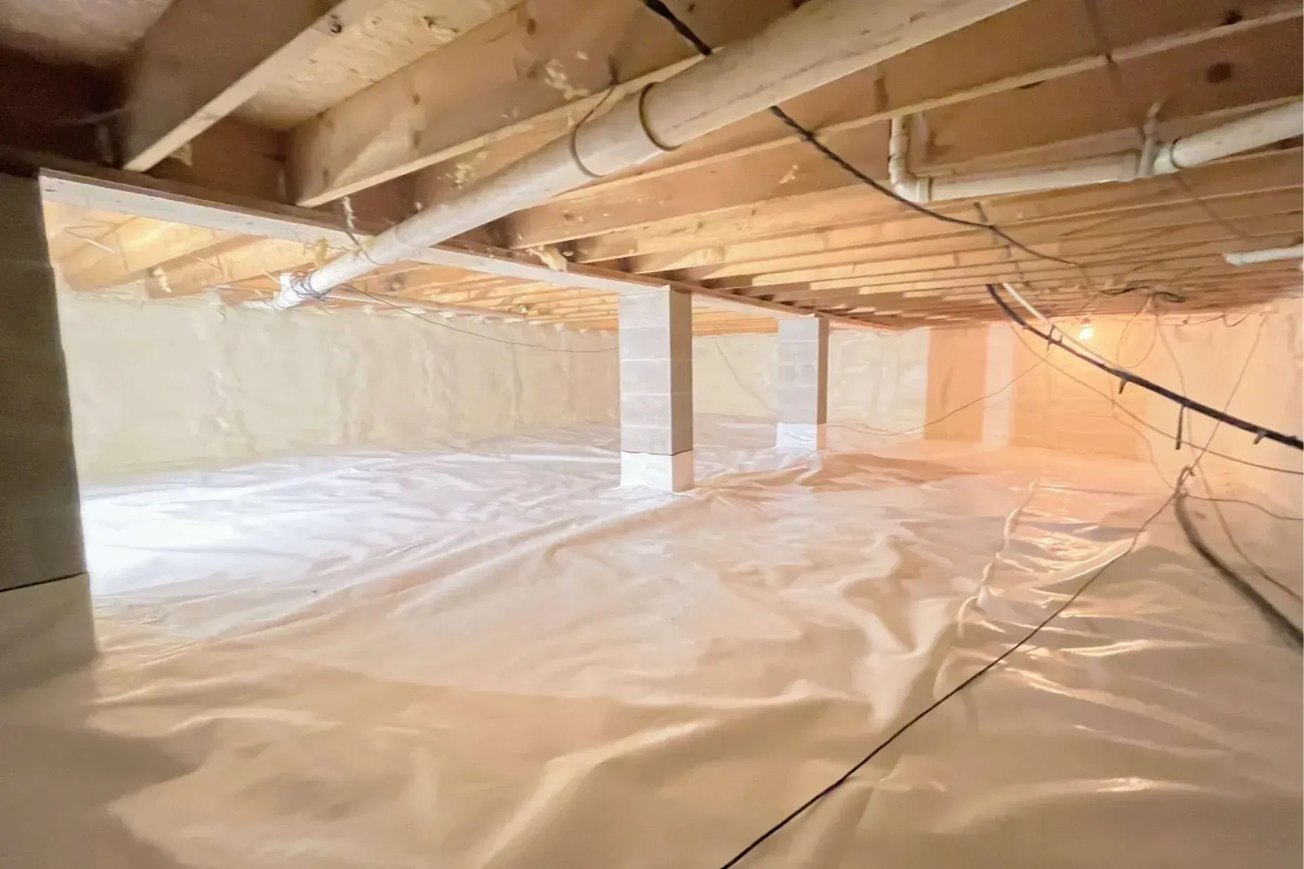 Encapsulated crawl space with a white liner over the ground and up the block piers and walls