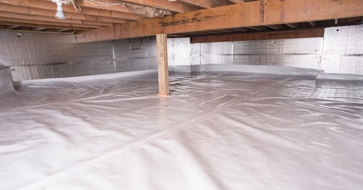 Crawl space vapor barrier laid across the ground beneath foil-insulated foundation walls