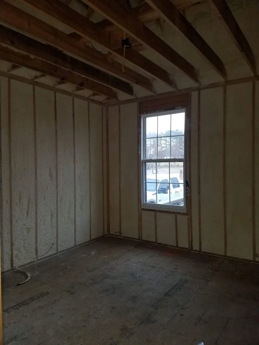 Framed room with spray foam insulation across the exterior walls and window opening