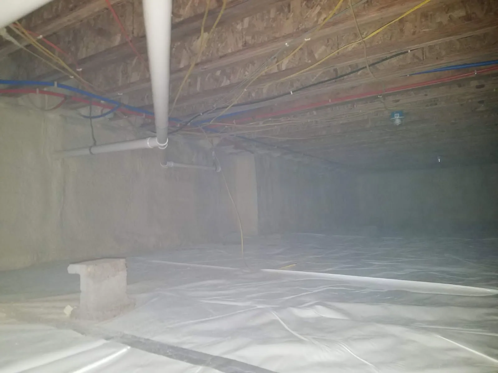Encapsulated crawl space with a vapor barrier running under the plumbing