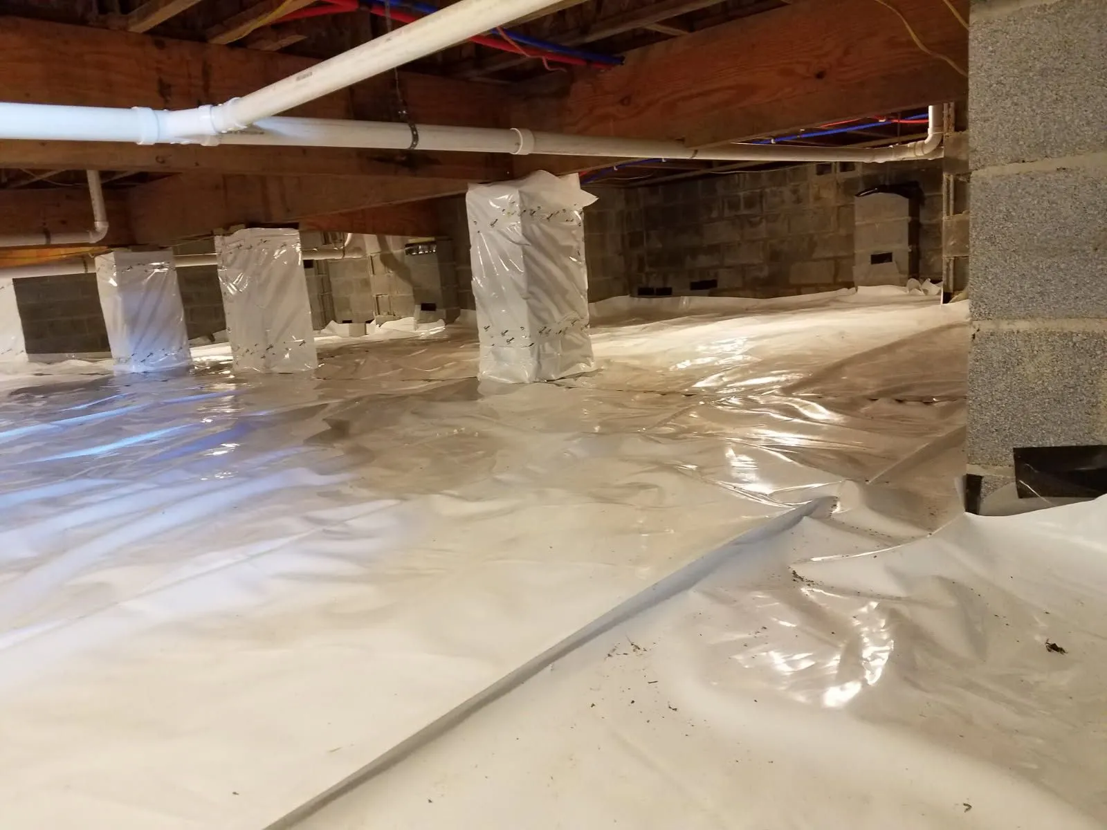 Encapsulated crawl space with a vapor barrier over the floor and wrapped piers