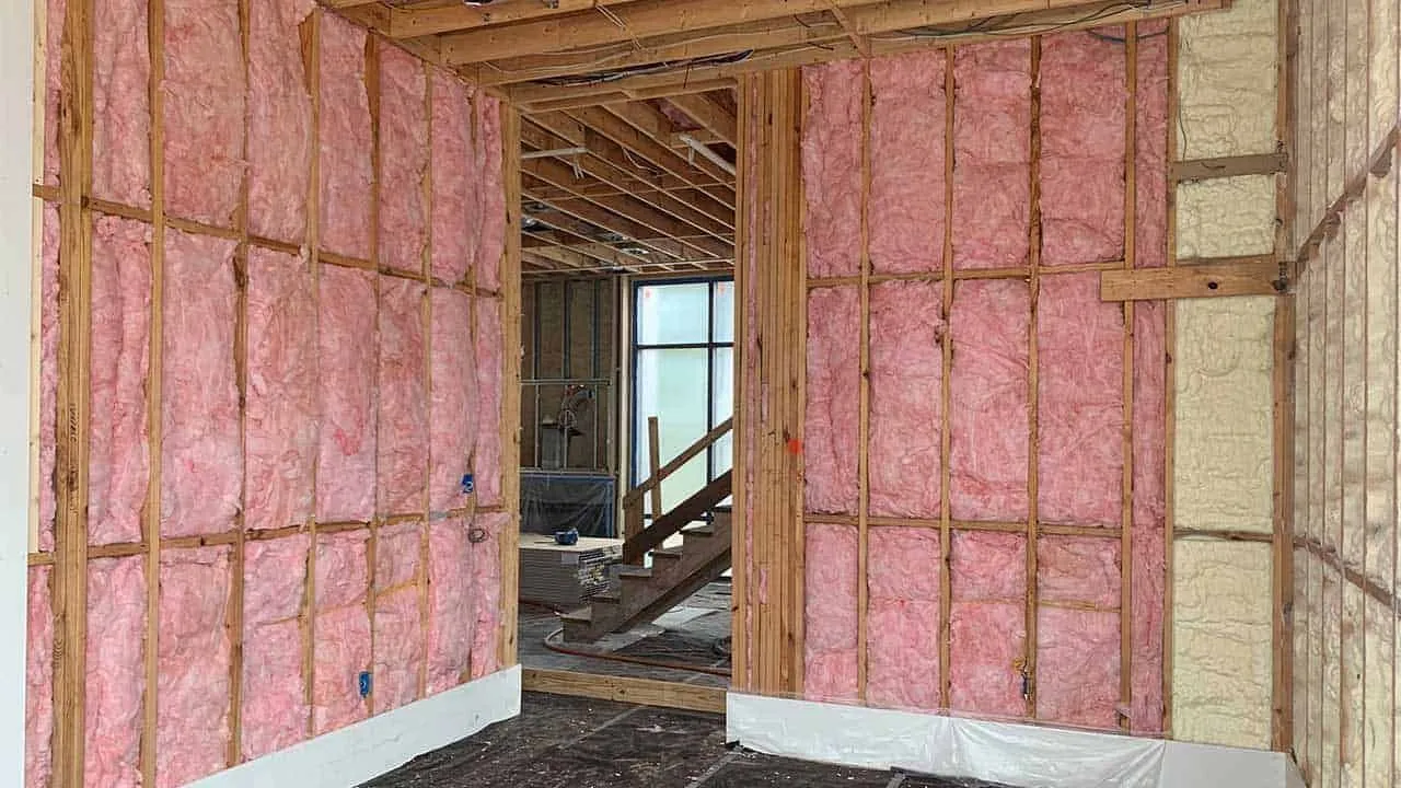 Pink fiberglass batt insulation in the framed walls of a house under construction