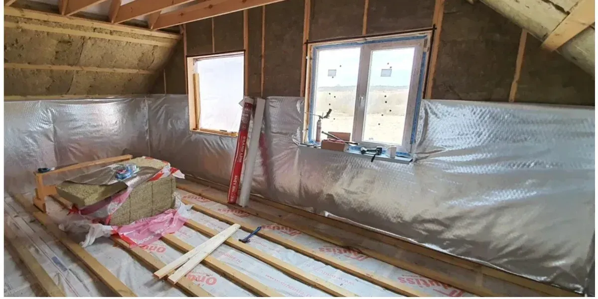 Loft under renovation with mineral wool between the rafters and foil-faced insulation along the knee walls