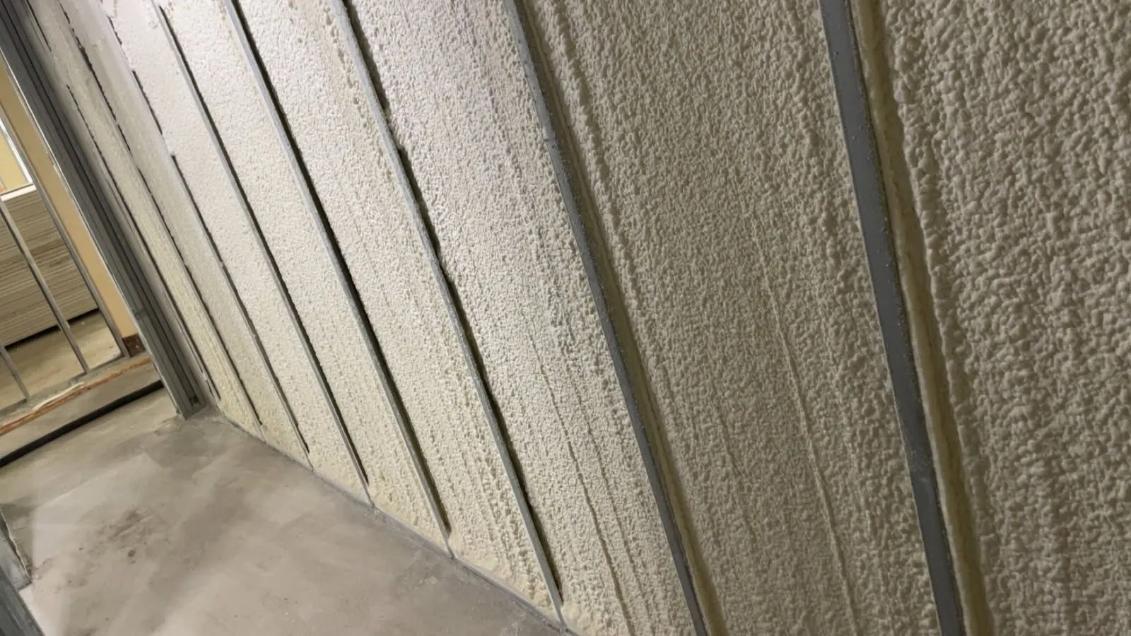 Spray foam insulation applied between steel wall studs on a commercial interior