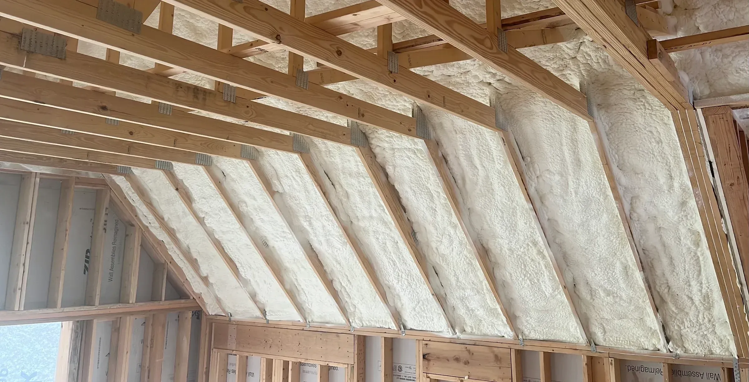 Spray foam insulation filling the rafter bays of a new roof deck above framed knee walls