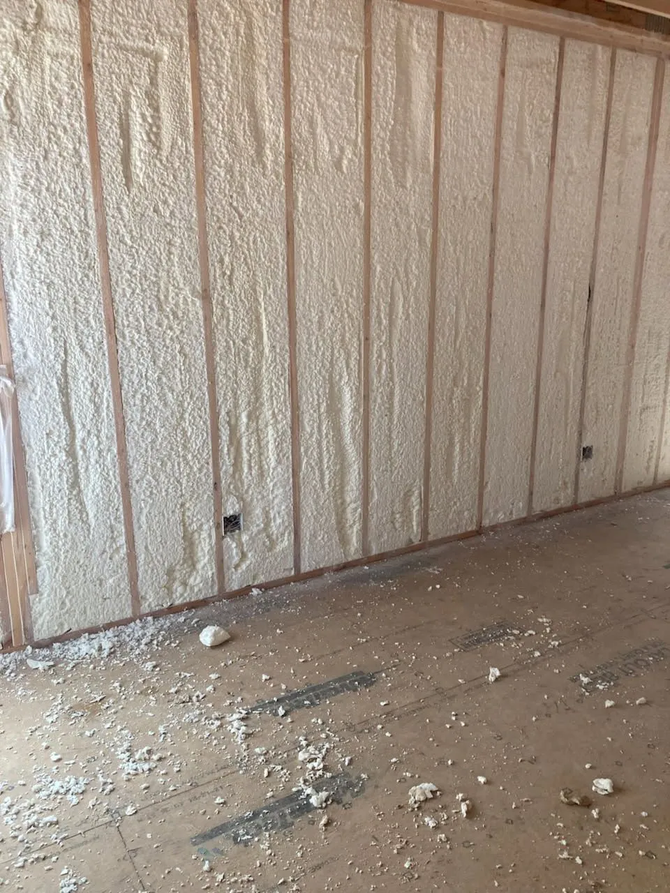 Spray foam insulation filling wood-framed wall cavities during a new build